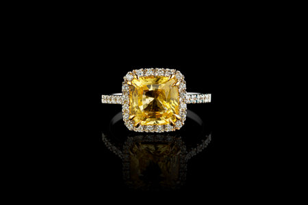 white gold ring with yellow sapphire stone, diamonds on black background close-upの写真素材