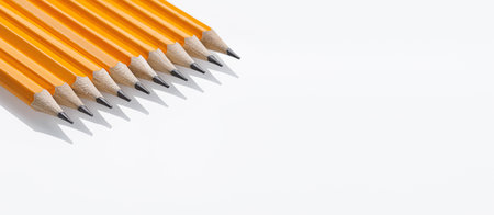 Close-up yellow graphite pencils with sharp tips lined up on a white background. Great for office use and art suppliesの写真素材