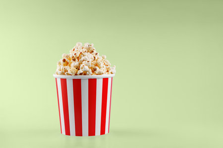 Classic red striped popcorn cardboard cup on Green background close-upの写真素材