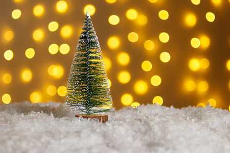 Christmas tree in snow with gifts on glowing lights bokeh background close upの写真素材