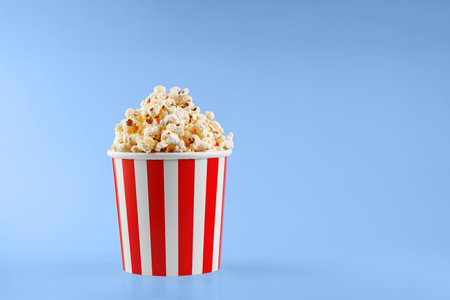 Classic red striped popcorn cardboard cup on blue background close-upの写真素材