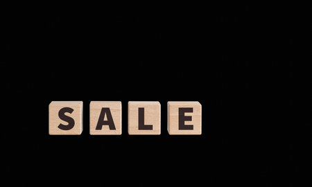 Wooden blocks with "SALE" text on a black background enhance advertising campaigns. Their bold texture stands out in promotional visuals.の写真素材