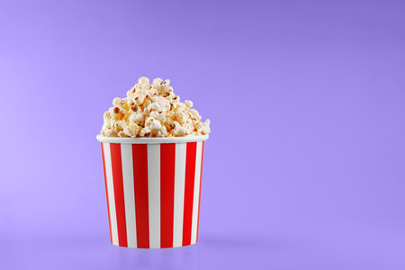 Classic red striped popcorn cardboard cup on Purple, violet background close-upの写真素材