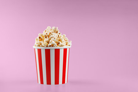 Classic red striped popcorn cardboard cup on Pink background close-upの写真素材