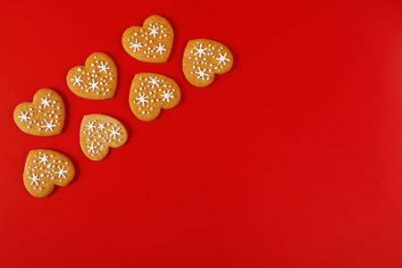 beautiful hand-baked cookies in the shape of a heart on a red background close-upの写真素材