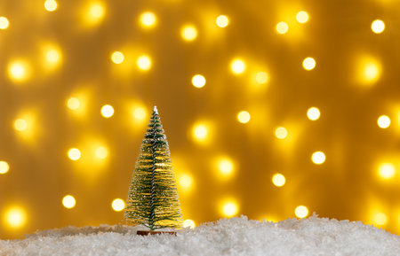 Christmas tree in snow with gifts on glowing lights bokeh background close upの写真素材