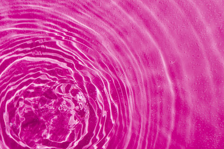 drops on water with circles on a pink background close upの写真素材