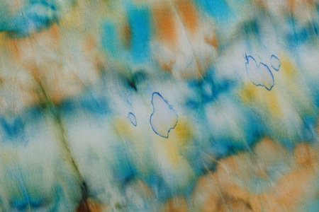 abstract pattern on silk fabric texture in blue, yellow, green colors close upの写真素材