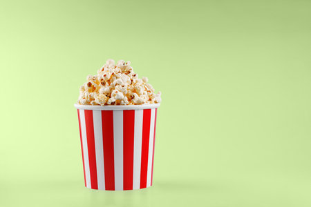 Classic red striped popcorn cardboard cup on Green background close-upの写真素材