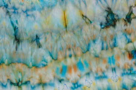 abstract pattern on silk fabric texture in blue, yellow, green colors close upの写真素材
