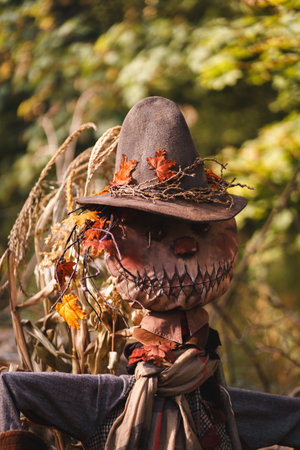 A mystical fall scene showcases a scarecrow guarding a vibrant pumpkin display on hay bales, with mist and a lantern creating an eerie yet warm atmosphere. Ideal for Halloween or autumn marketing.の写真素材