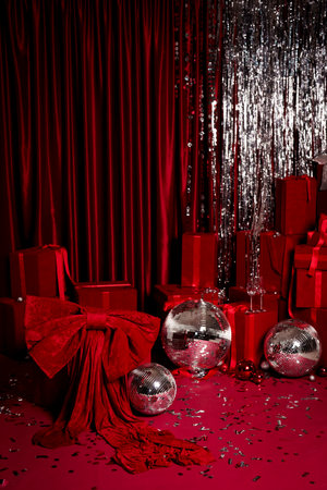 Luxurious red holiday scene with wrapped gifts, disco balls, sparkling tinsel and confetti. Perfect for party ads, banners, product mockups and Christmas campaigns.の写真素材