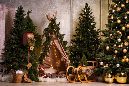 Festive indoor scene showing a kids' teepee surrounded by fir trees, fairy lights and a wooden sled - ideal for family lifestyle, parenting blogs and seasonal ecommerce.の写真素材