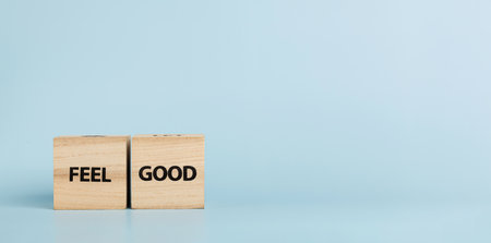 Wooden cubes with inscriptions Feel Good on a blue background close-upの写真素材