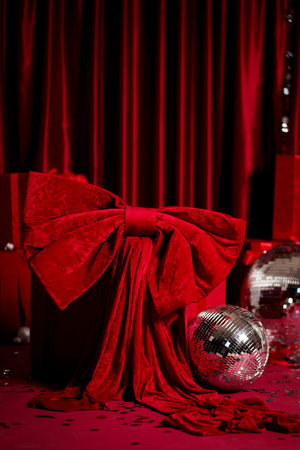 Luxurious red holiday scene with wrapped gifts, disco balls, sparkling tinsel and confetti. Perfect for party ads, banners, product mockups and Christmas campaigns.の写真素材