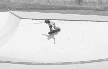 young skateboarder skating in large cement bowl