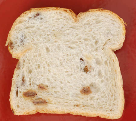single slice of raisin bread on red background
