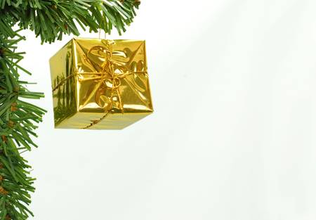 gold foil wrapped christmas present dangling from christmas tree branchの写真素材