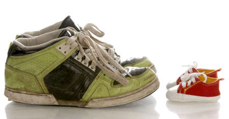 big old shoes and new baby or infant shoes の写真素材