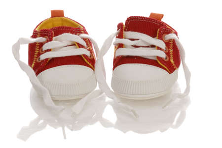 red infant or baby running shoes with reflection on white backgroundの写真素材