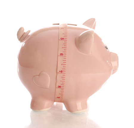 pink piggy bank with measuring tape with reflection on white backgroundの写真素材