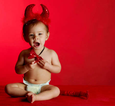adorable baby dressed up like a devil on red backgroundの写真素材