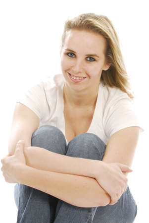 young woman wearing braces sitting hugging knees on white backgroundの写真素材