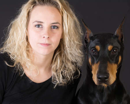portrait of attractive woman and doberman pinscher dog on black backgroundの写真素材