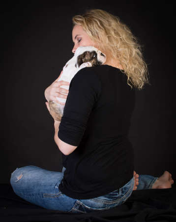 woman hugging new puppy on black background - 8 week old bulldogの写真素材