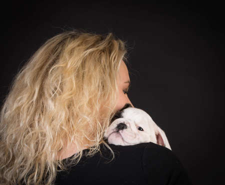 woman hugging new puppy on black background - 8 week old bulldogの写真素材