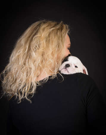 woman holding young puppy in her arms on black backgroundの写真素材
