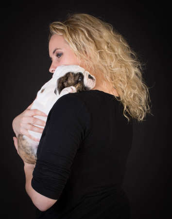 woman hugging new puppy on black background - 8 week old bulldogの写真素材