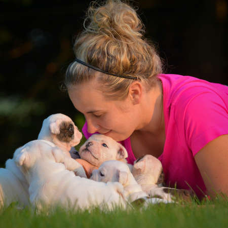 woman playing in the grass with litter of puppiesの写真素材