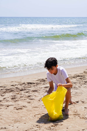 preteen volunteer, taking a walk on the beach in summer, collecting plastic from the seashore.の写真素材