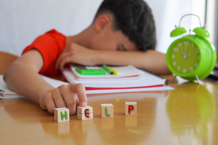 child with learning difficulties in school, frustrated doing homework, asking for help and attention to his problemの写真素材
