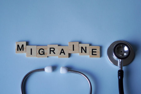 MIGRAINE, wooden letters and stethoscope with a soft blue backgroundの写真素材