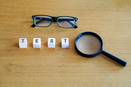 writing cabbage letters on wooden cubes with magnifying glass and glasses on wooden tableの写真素材