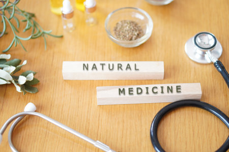 NATURAL MEDICINE written on wooden blocks on a table with plants, herbs, natural oils and a stethoscope.の写真素材