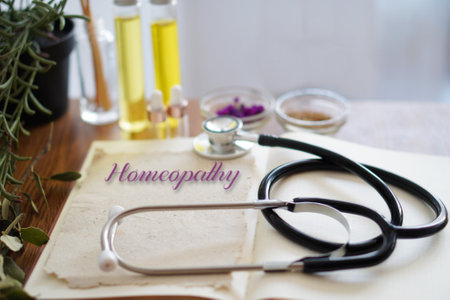 HOMEOPATHY essentials. open book with stethoscope, oils and natural remedies.の写真素材