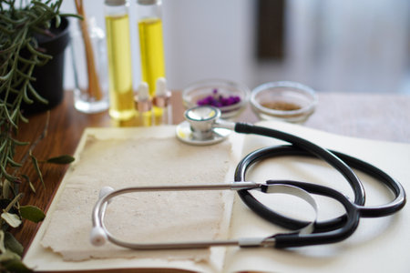 open book on a homeopath's table with stethoscope, herbs and oilsの写真素材