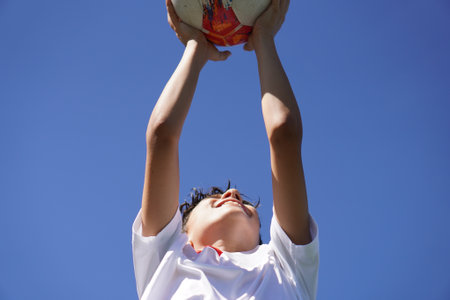 close-up of a boy holding a soccer ball in sports clothesの写真素材