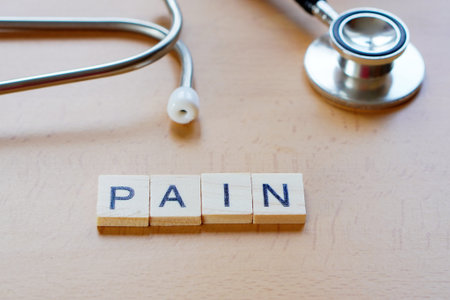 medical concepts. PAIN. word written in wooden letters next to a stethoscope.の写真素材