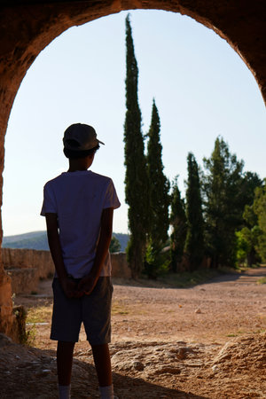 travel and vacation. teenage boy with his back to the arch of a stone wall.