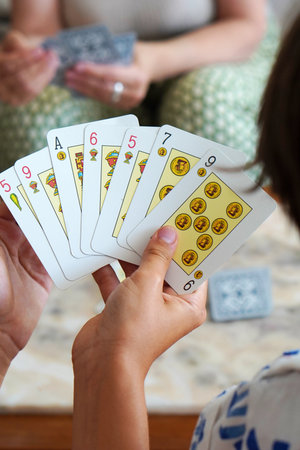 close up of children playing with their grandmother at cards with Spanish deck of cards