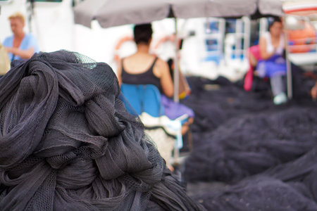 fishing industry. traditional trades. pile of nets stacked with women net menders repairing and sewing nets.の写真素材