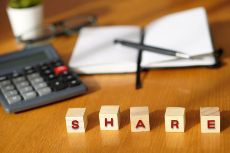 SHARE, financial concepts. Letters written on wooden blocks with a calculator and notebook in the backgroundの写真素材