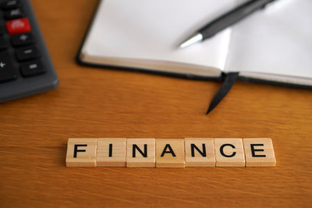 FINANCE. Financial concepts. Wooden letters with calculator and notebook in the background.の写真素材