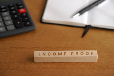 income proof. financial concepts. words written on a wooden block with a calculator, notebook, and...