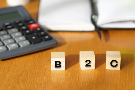 B2C. Financial and business concepts. Letters on wooden blocks with a calculator and notebook in the...