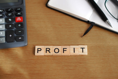 profit. financial concepts. wooden letters with calculator, notebook, and pen in the background